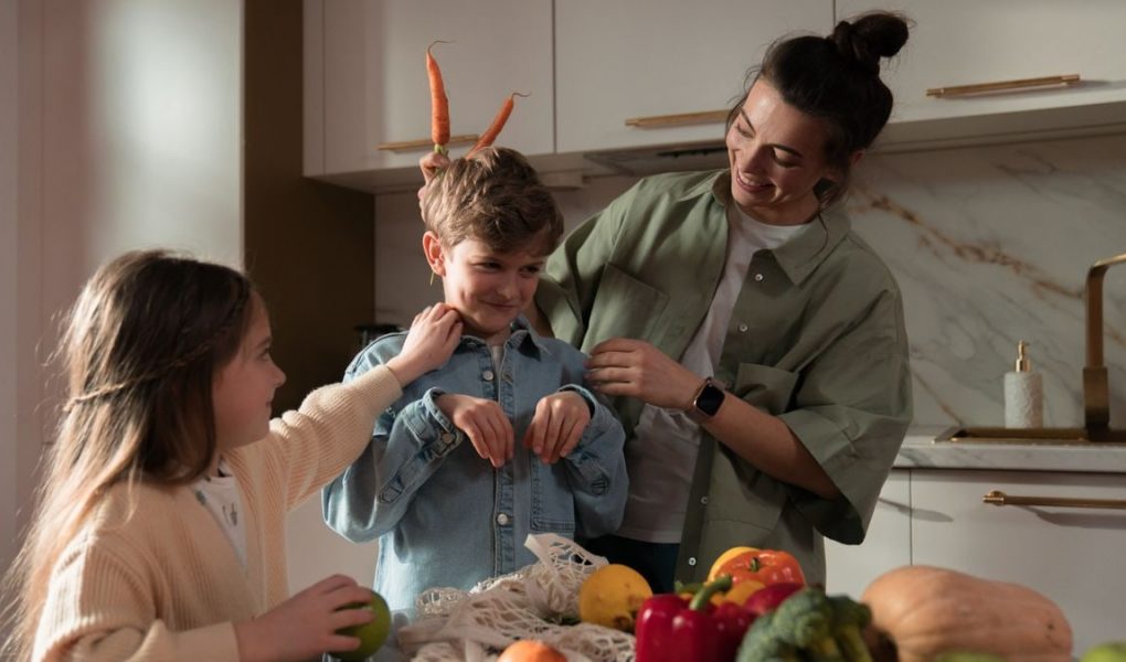 Mother and children have fun unpacking vegetables in the kitchen.