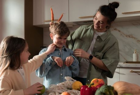 Mother and children have fun unpacking vegetables in the kitchen.